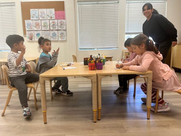 Preschoolers drawing with a teacher at Our Second Home