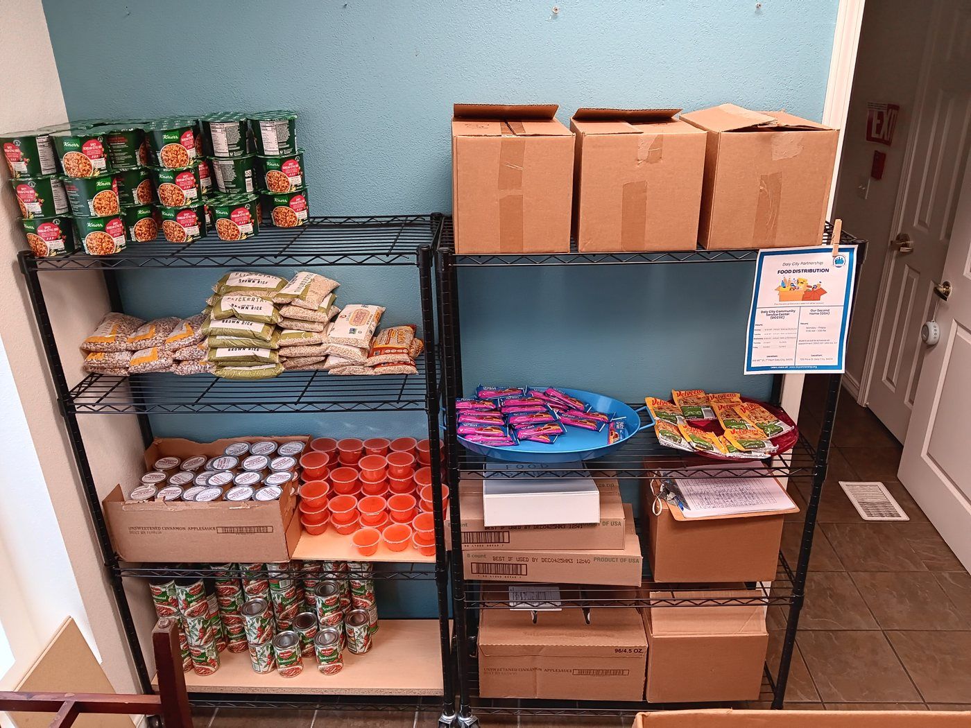 Stocked shelves at the drop-in pantry — rice, pasta, canned goods, and boxes ready to go