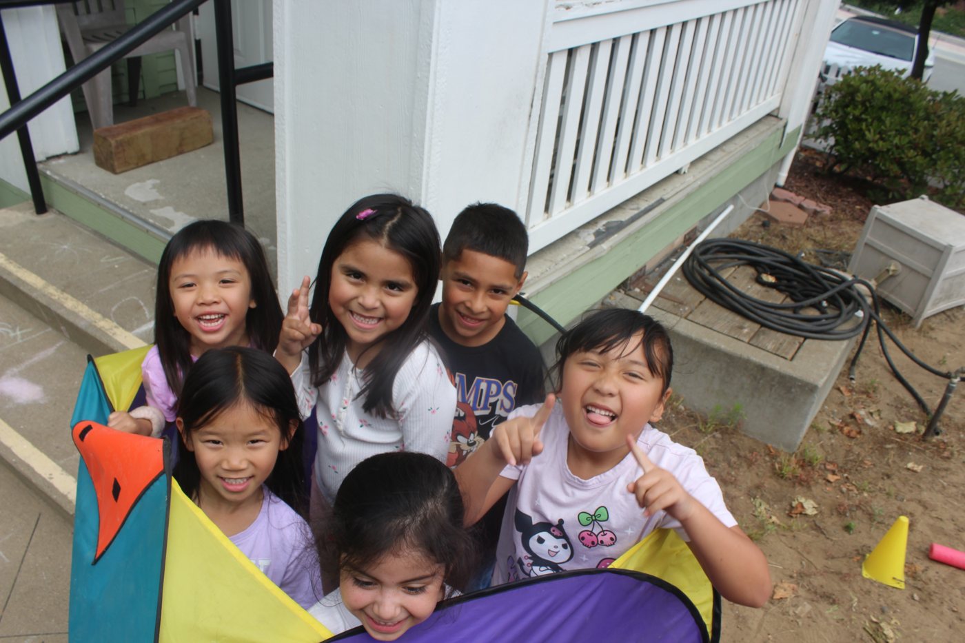 Kids laughing outdoors with a play tent at summer camp