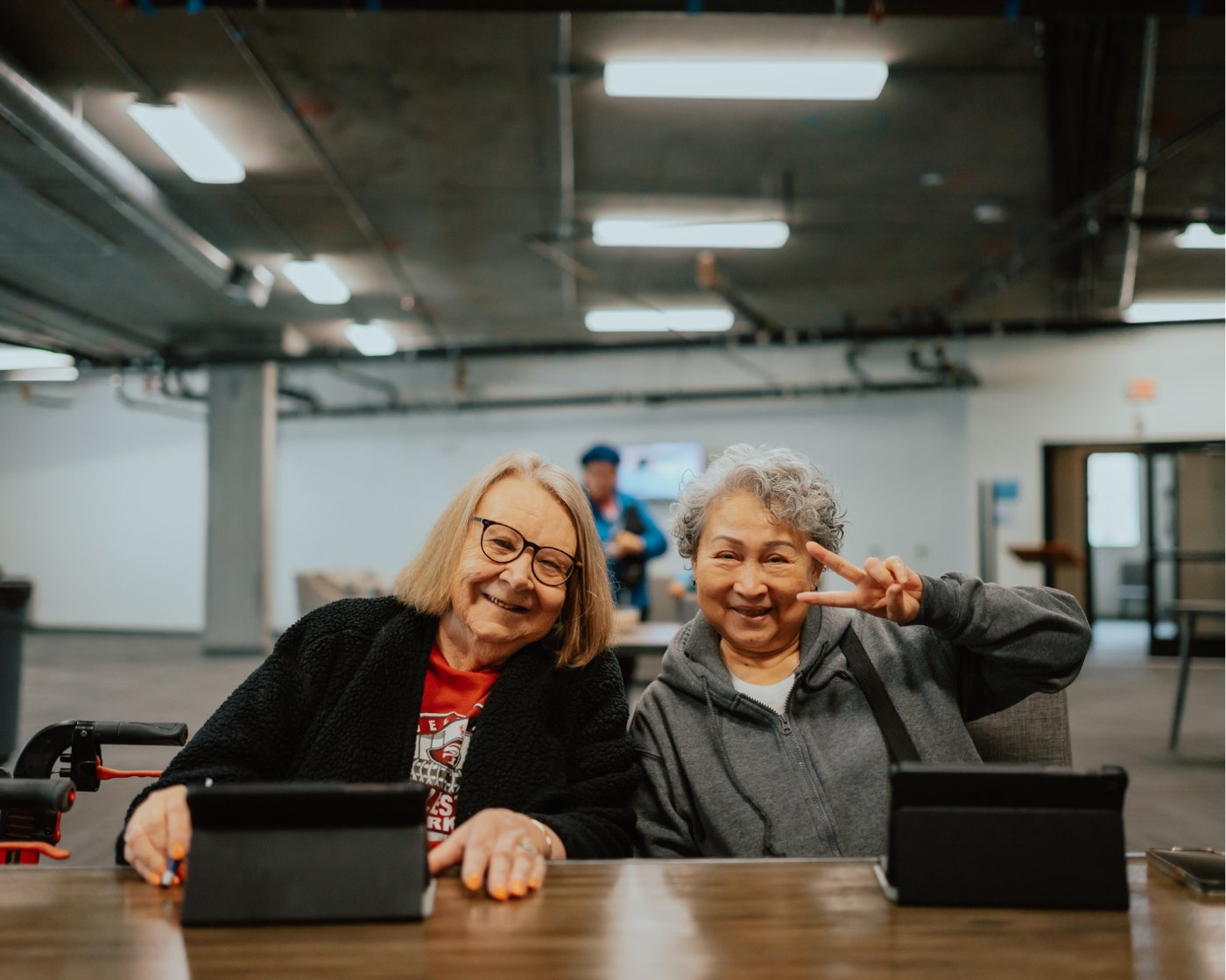Two seniors smiling at a digital literacy class with tablets