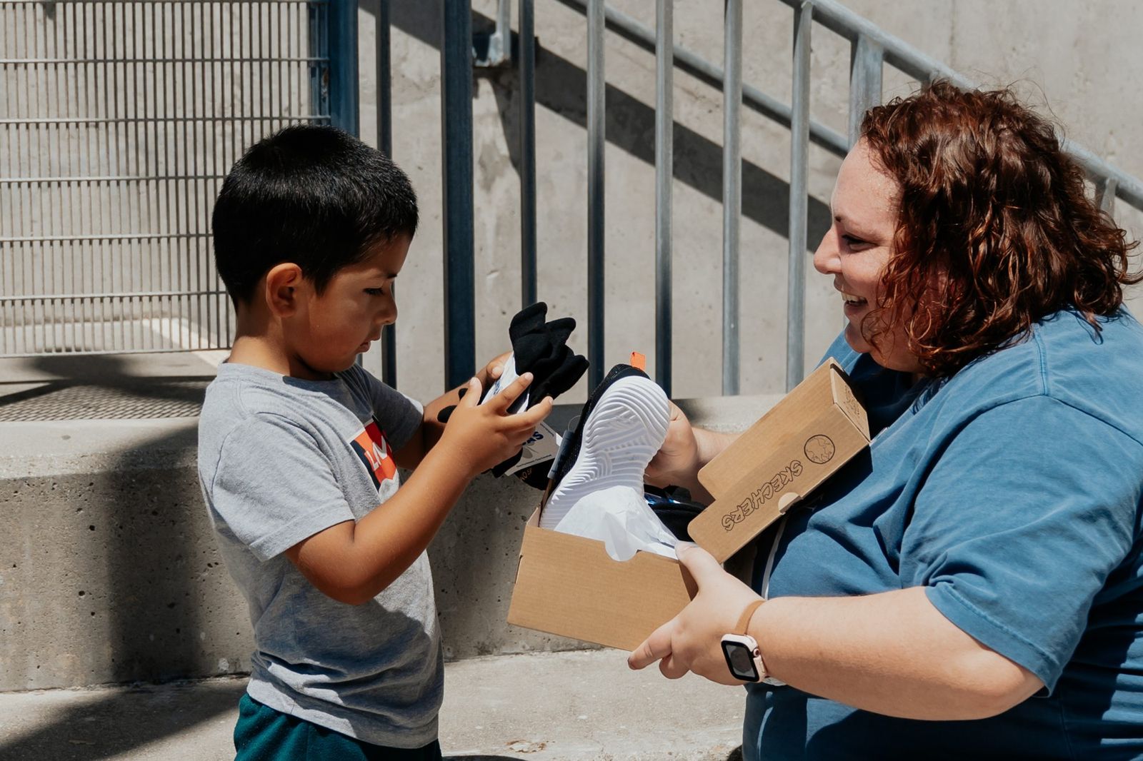 A volunteer helping a young boy try on new shoes at Family Resource Day