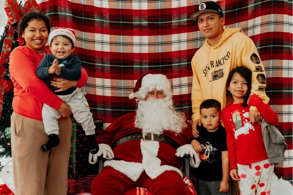 A family smiling with Santa at Presents with Purpose 2025